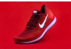 Red Nike shoe, tip on the ground, heel up, on red background
