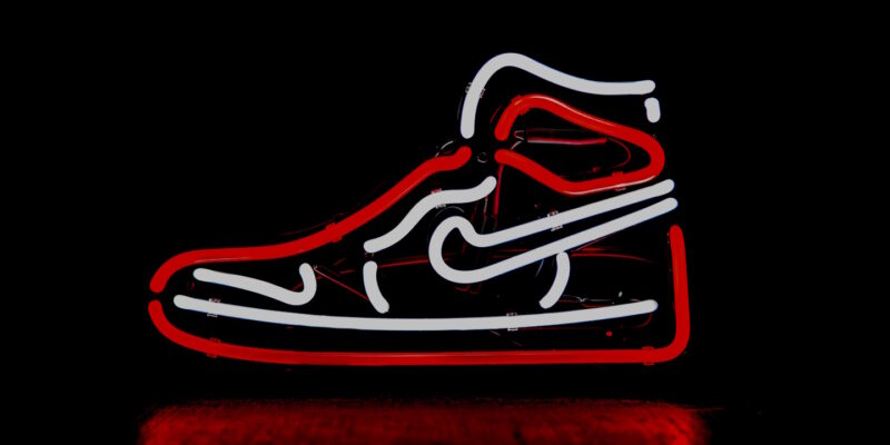 Athlectic-shoe-shaped neon sign red and white on dark background